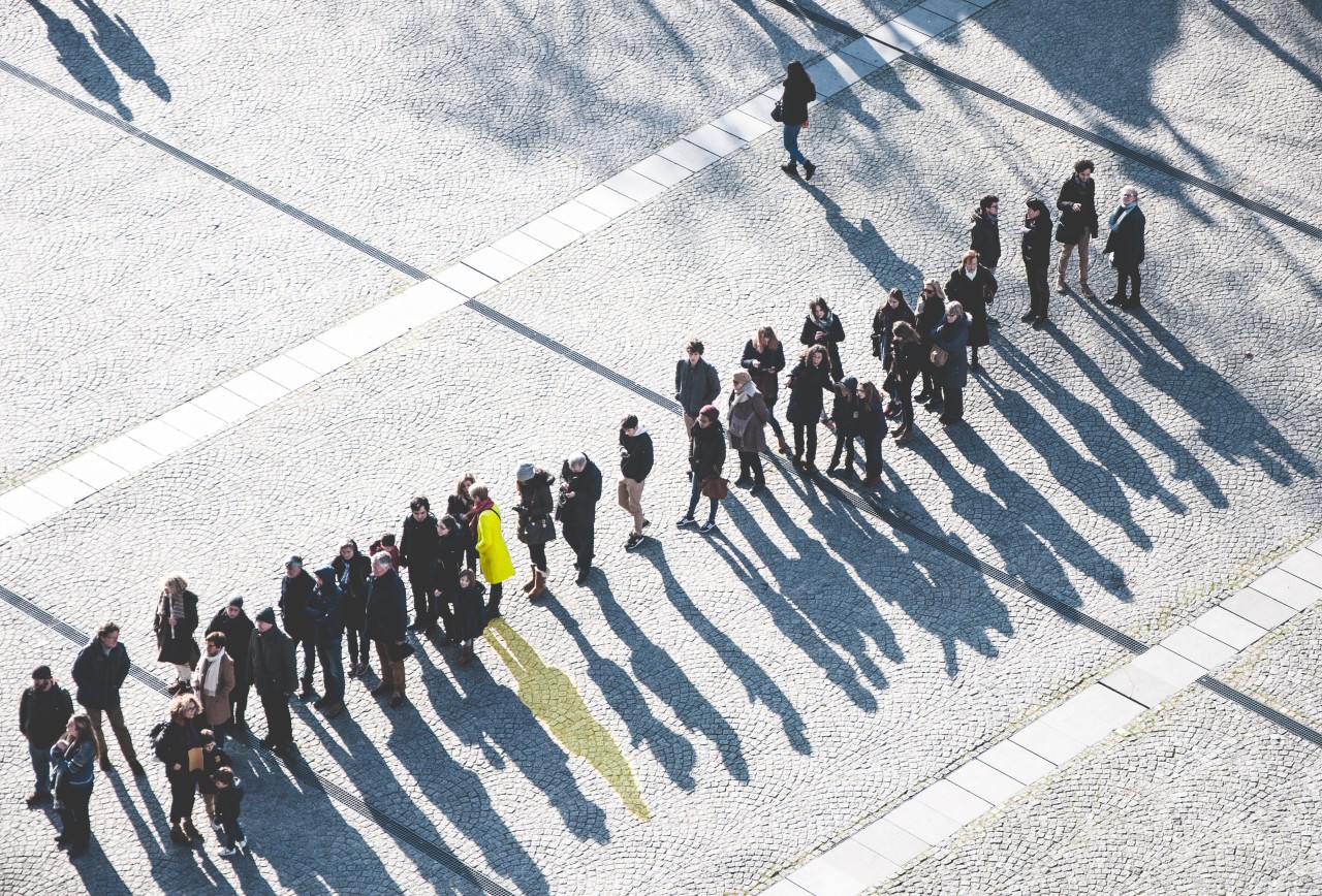 People waiting in a long line and observing an event. People